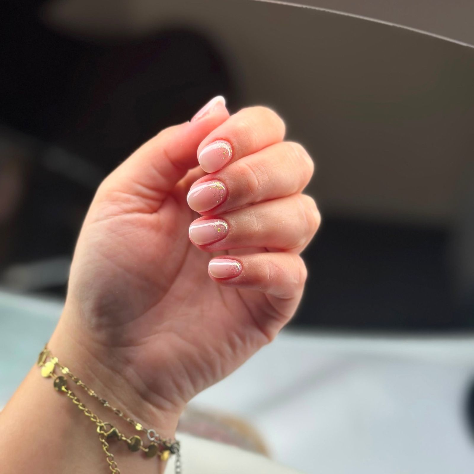Korte nude nagels met witte tips en een gouden armband
