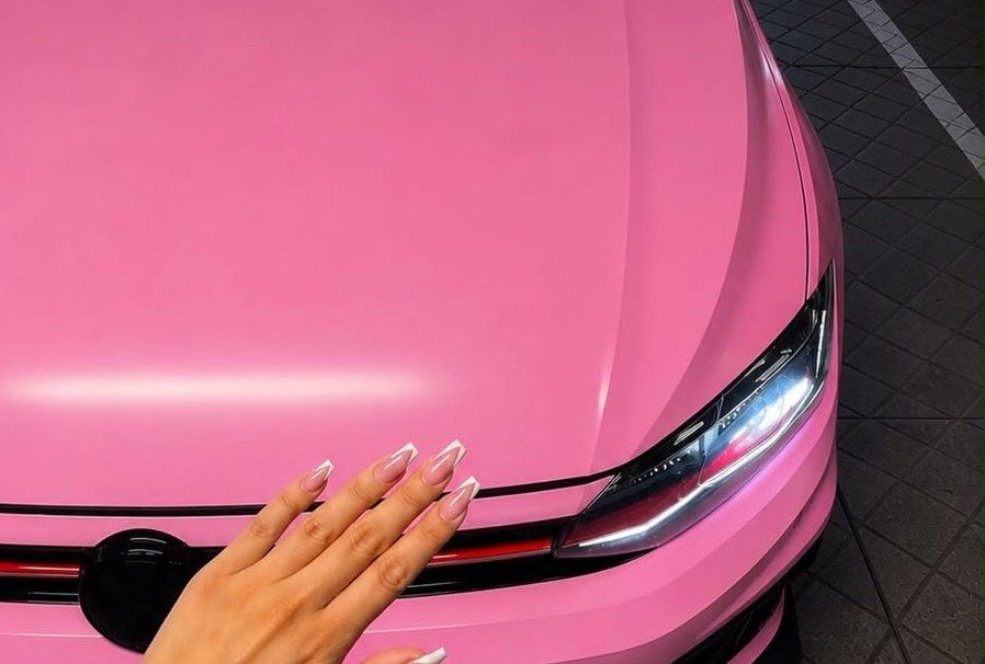 Nude french nagels op de motorkap van een roze auto